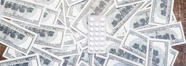Comprimidos en un paquete de billetes. El aumento en el costo del tratamiento debido a la guerra entre Ucrania y Rusia - Foto, imagen