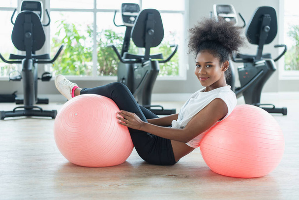 happy african american woman with a curly afro hairstyle in a gym relaxing after pilates workout - Photo, Image