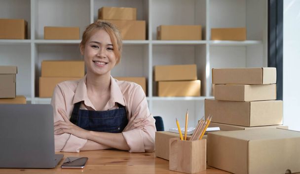 Joven sonriente belleza propietario asiático mujer freelancer sme negocio de compras en línea de trabajo en el ordenador portátil con caja de paquetes en casa - PYME negocio en línea y entrega concep - Foto, imagen