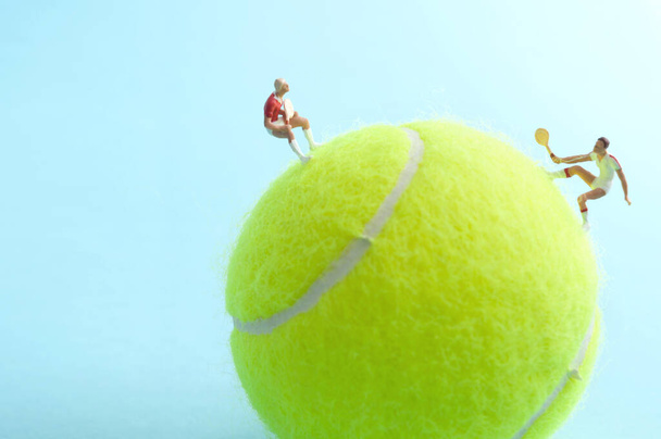 Two miniature tennis players on top of a ball competing in a match - Φωτογραφία, εικόνα