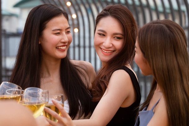 mujer asiática adolescentes vitoreando y tostadas con copa de vino espumoso blanco para celebrar en la cena en verano. concepto de celebración, relación y amistad. - Foto, imagen