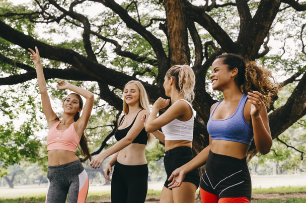 onnellinen nuori monietninen naiset teini ystäviä ryhmä rentouttava ja tanssia harjoituksen jälkeen puistossa viikonloppuna aamulla. elämä jälkeen covid. - Valokuva, kuva