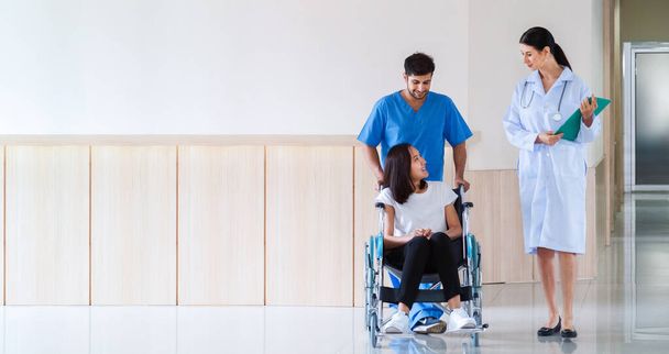 szczęśliwa uśmiechnięta azjatycka pacjentka siedząca na wózku inwalidzkim z pielęgniarką rozmawiającą z lekarzem po powrocie do zdrowia z planu leczenia operacyjnego w szpitalu. opieka zdrowotna i pojęcie medyczne - Zdjęcie, obraz
