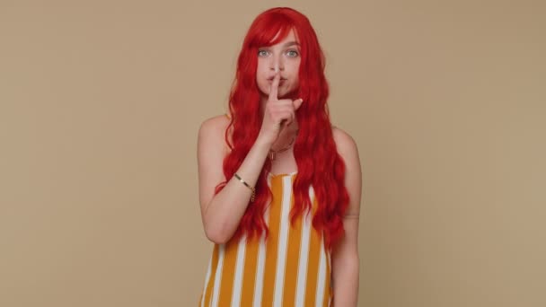 Sessiz olun lütfen. 20 'li yaşlardaki kızıl saçlı kadının portresi işaret parmağını dudaklara bastırıyor. Sessizlik işareti gizli tutulmasını sağlıyor. Genç, güzel, kızıl kız bej renkli stüdyo arka planında yalnız poz veriyor. - Video, Çekim