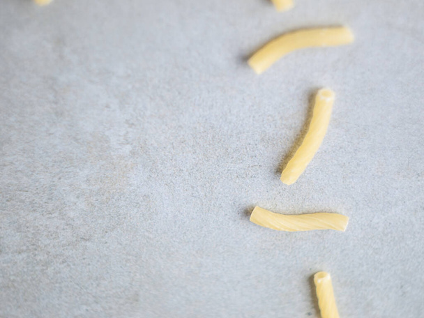 Closeup of Italian food yellow raw uncooked vermicelli, macaroni, noodle, pastry, pasta on the isolated gray tile (close-up,meal, cuisine, cooking, gray, dry, dish, studio, plate, dinner, tile, cement) - Foto, Imagen