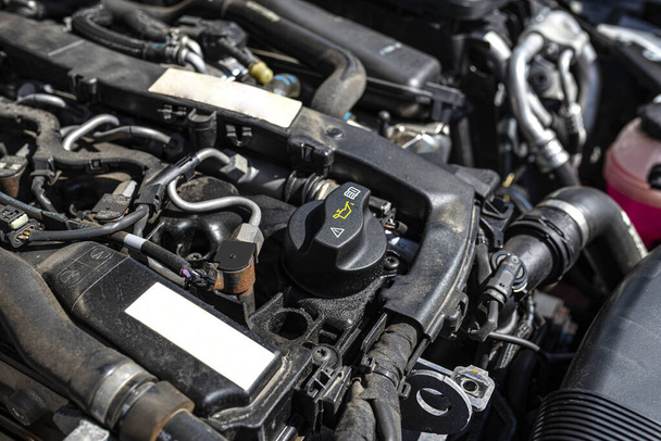 Compartimento del motor en un coche diesel, relleno de aceite cerrado visible en negro y piezas del motor. - Foto, Imagen