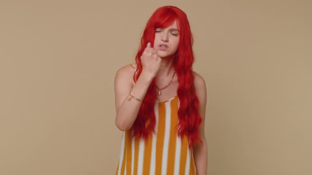 Aggressive angry ginger woman in tank top trying to fight at camera, shaking fist, boxing with expression, punishment, disappointment. Young redhead girl isolated alone on beige studio wall background - Footage, Video