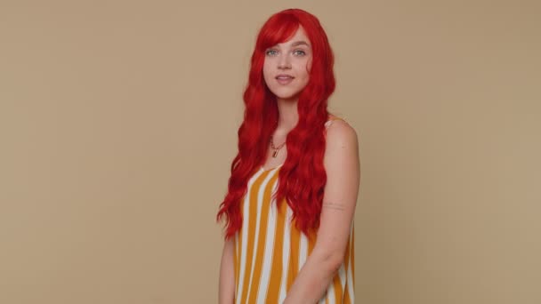 Wow Hello. Redhead woman smiling friendly at camera and waving hands gesturing hello or goodbye to friend, welcoming with hospitable expression. Young happy girl indoors isolated on beige background - Footage, Video