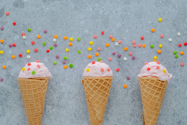 Розовое мороженое в роге посыпать цветными звездами на сером фоне. Концепция летнего и сладкого меню, плоская раскладка, место для текста. Высокое качество фото - Фото, изображение