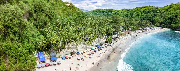 Magnifique photo panoramique aérienne de la plage tropicale au bout de la vallée de montagne avec cocotiers, bateaux en eau bleue, touristes non reconnus, plage de Crystal Bay, Nusa Penida, Bali - Photo, image
