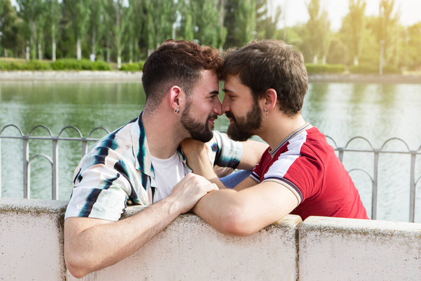 Casal gay sentado em um banco de parque, olhando nos olhos uns dos outros. .. Foto de alta qualidade - Foto, Imagem