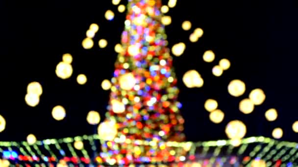 Nagy szilveszterkor karácsonyfa díszített világító sokszínű koszorúk és megvilágítás éjjel. Karácsonyfa villogó fényekkel. Homályos háttér. Újévi és karácsonyi ünnepek - Felvétel, videó