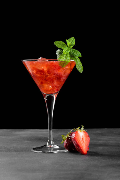 Cocktail froid d'été aux fraises mojito, margarita, daiquiri dans une glasse de martini. Boisson fraise fraîche avec glaçons et feuilles de menthe sur fond sombre. Limonade aux fraises glacées - Photo, image