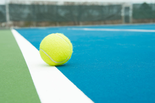Zijaanzicht van een tennisbal die aan de binnenkant van de zijlijn landt. - Foto, afbeelding