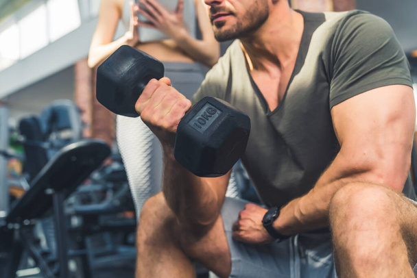 Musculoso joven levantando pesas en el interior del gimnasio, foto de cerca. Foto de alta calidad - Foto, imagen