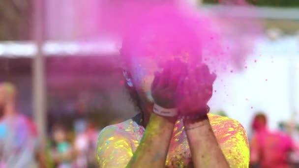 Щаслива дівчина, що тримає кольоровий порошок у руках, випускає фарби в камеру на фестивалі Холі.. - Кадри, відео