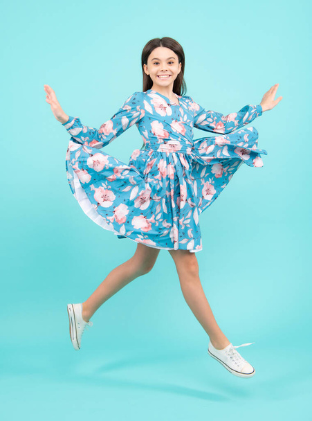 Full length cheerful teenager kid jump enjoy rejoice win isolated on blue background. Small child girl in summer dress jumping. Excited teenager, amazed and cheerful emotions - Foto, imagen