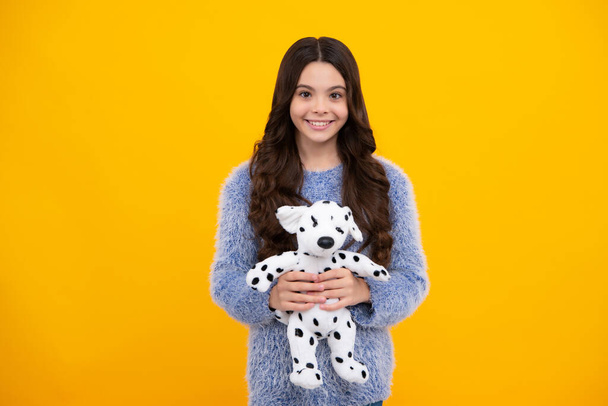 Teenager girl 12, 13, 14 year old hold soft toy for birthday on yellow background. Kid with her toys. Happy teenager, positive and smiling emotions of teen girl - Photo, Image