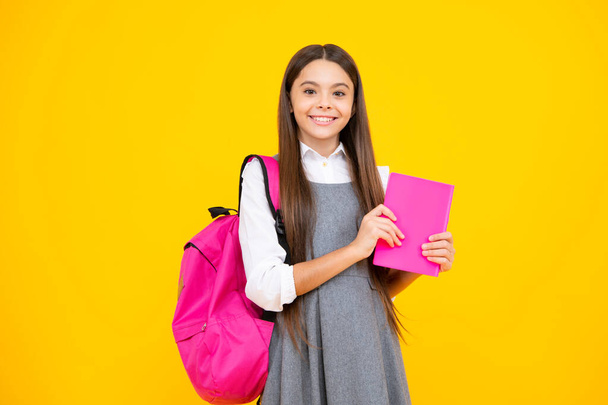 学校に戻る。女子学生は黄色の孤立したスタジオの背景に本を保持します。学校と教育の概念。十代の女の子で学校制服 - 写真・画像