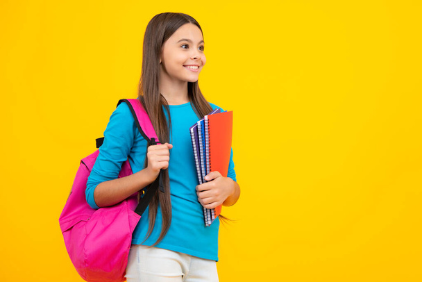 Back to school. Teenager schoolgirl hold book and copybook ready to learn. School children on isolated yellow studio background. Happy teenager portrait. Smiling girl - Foto, Bild