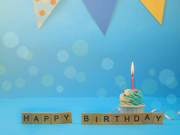 Sweet cupcake and bow candle on blue background with copy space. Happy birthday party - Фото, зображення