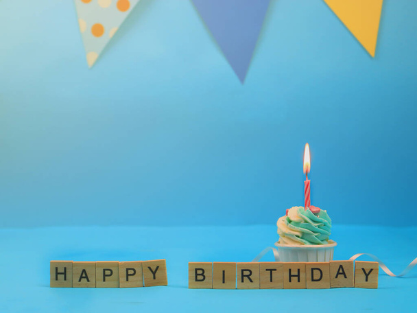 Sweet cupcake and bow candle on blue background with copy space. Happy birthday party - Photo, Image