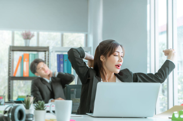 Kobieta azjatycki bizneswoman pracownik rozciąga się i ziewa w miejscu pracy biurowej, po długim czasie sennej pracy. - Zdjęcie, obraz