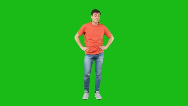 Pełne ciało zaskoczonego mężczyzny dotykając twarzy i patrząc w odległości z wstrząśniętej twarzy izolowane na zielonym tle w studio - Materiał filmowy, wideo