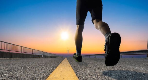 a man as athlete runner in high speed running action on the road toward the sunrise with bright sky backgroun - Foto, imagen