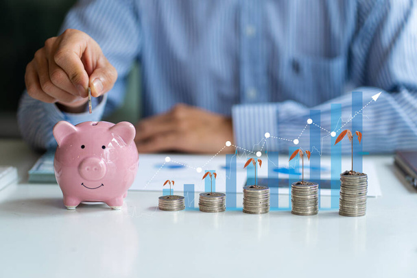 a businessman holding a coin in a piggy bank and a pile of coins with a graph of good investment or savings ideas Financial Analysis Planning for Corporate Growth - Valokuva, kuva