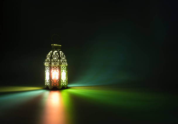Candle light lids on muslim style's lantern shining on floor with colorful vintage pattern on surface, use as greeting on ramadan kareem mubarak - Photo, Image
