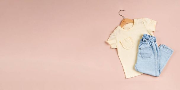 Childish image with jeans and a yellow t-shirt on a pink background. Flat lay. - Photo, image