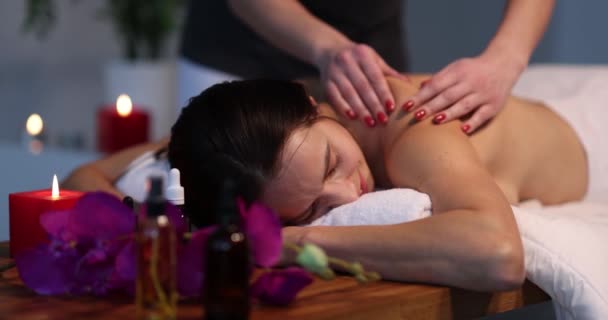 Profesjonalny masażysta wykonuje terapeutyczny masaż pleców kobiecie w spa. Młoda kobieta dostaje relaksujący masaż ciała - Materiał filmowy, wideo