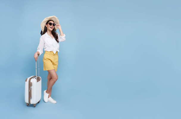 青の背景に隔離された休日に旅行に行く荷物を保持する幸せな若いアジアの観光客の女性。コピースペース - 写真・画像