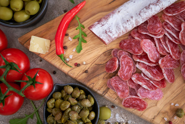 Sliced Spanish sausage fuet salami and vegetables on a domestic kitchen. - 写真・画像