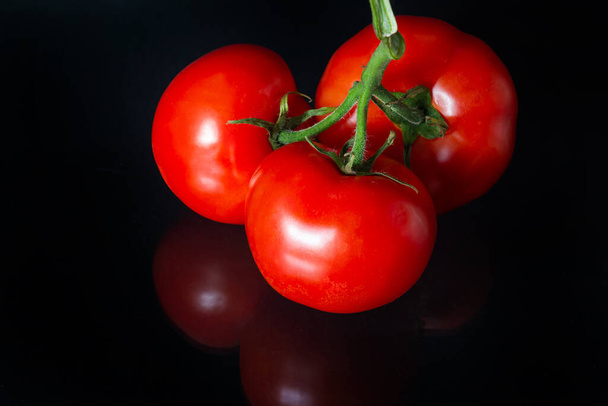 Red row ripe tomatoes with drops of water luminating. Fresh Appetizing natural antioxidants in tasty tomatoes. Heap of Tomatoes isolated on black background. - Foto, Imagen