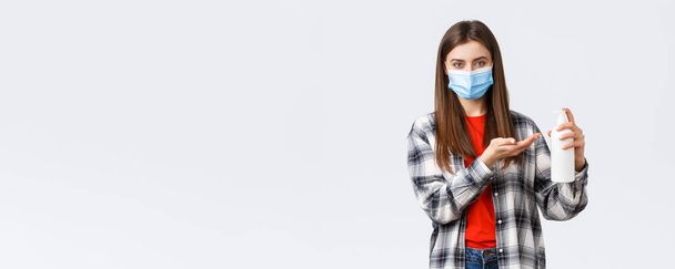 Coronavirus járvány, szabadidő karantén, társadalmi távolság és az érzelmek koncepciója. A fiatal nő gondoskodik az egészségről, megelőzi a vírusfertőzést, szappant vagy kézfertőtlenítőt alkalmaz, orvosi maszkot visel. - Fotó, kép
