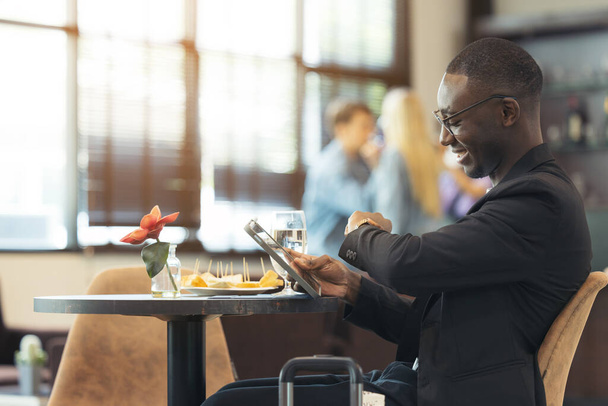 Un uomo d'affari nero lavora sul suo portatile in un caffè. - Foto, immagini