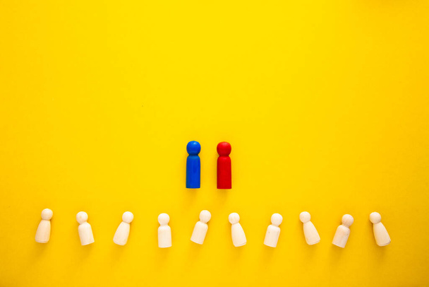 Wooden figures on yellow background. Concept of supremacy leader - Photo, Image