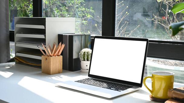 Комфортний домашній офісний стіл з портативним комп'ютером, кімнатним рослинництвом та приладдям
. - Фото, зображення