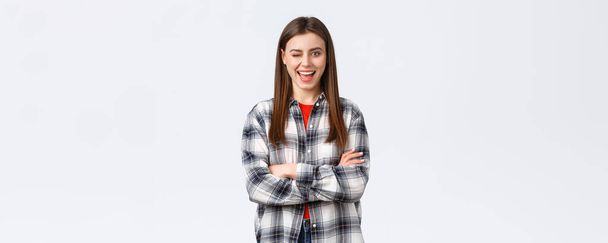 Lifestyle, different emotions, leisure activities concept. Enthusiastic and confident attractive woman, female student in checked casual shirt winking excited and smiling, cross arms chest ready. - Foto, Bild