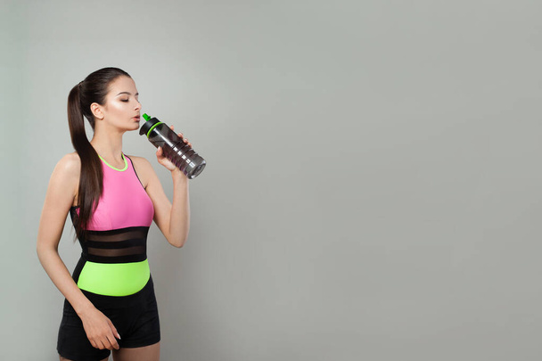 Mujer en forma activa con botella de agua o batido de proteínas después de ejercicios de fitness en interiores - Foto, Imagen