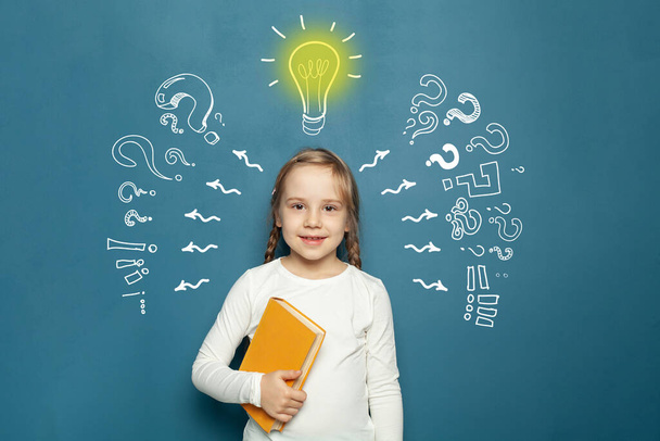 Cute happy kid with chalk drawing lightbulb, arrow and question mark. Education, success, idea and innovation concept - Fotoğraf, Görsel