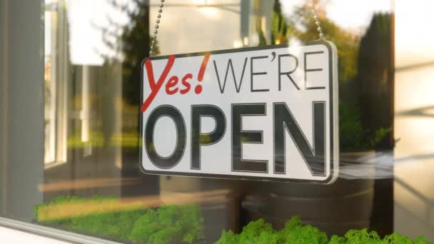 Yes We Are Open hanging sign sways from side to side on a storefront window. Seamless loop footage - Footage, Video