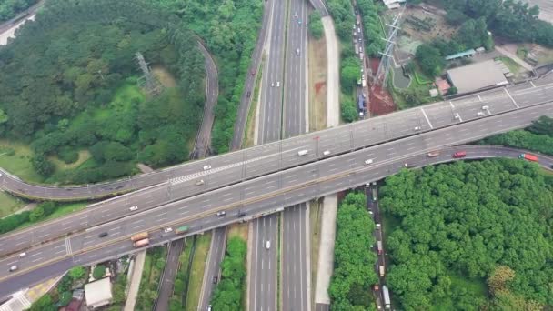 Aerial flyover car traffic roundabout interchange road in evening, drone shot top down roadway intersection in city. Lot of cars driving busy junction highway. Summer day, green trees grass. - Footage, Video