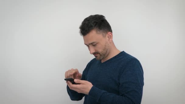 Handsome bearded Man Browsing Smartphone isolated on White Background. Attractive caucasian middle aged man uses phone, copy space - Felvétel, videó