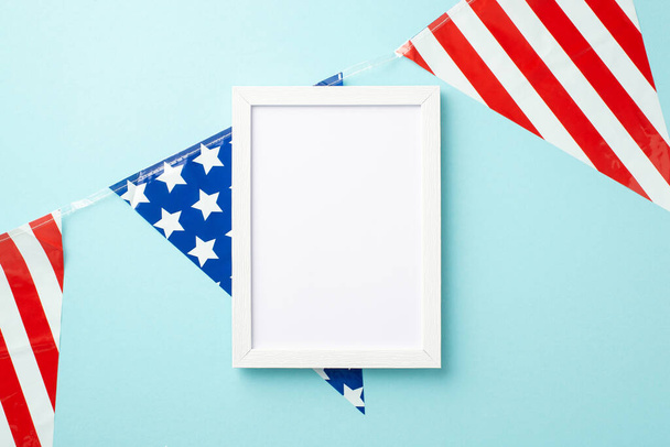 USA Independence Day concept. Nahoru pohled fotografie rámu fotografie a národní vlajka věnce na izolované pastelové modré pozadí s prázdným prostorem - Fotografie, Obrázek