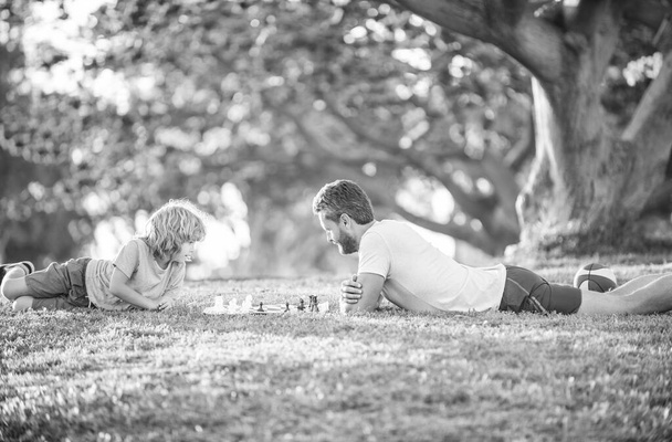 Šach mat. spolu trávit čas. strategický a taktický. doučování. Táta a kluk hrají logickou hru. otec a syn hrají šachy na trávě v parku. Den otců. Šťastná rodina. rodičovství a dětství. - Fotografie, Obrázek