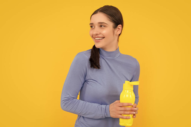 happy young woman holding sport bottle with water, thirst. - Photo, Image