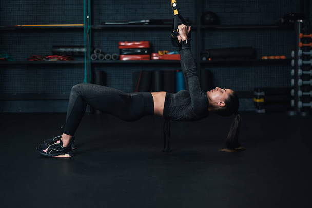 Η αθλήτρια γυμνάζεται στο γυμναστήριο. σκούρο φόντο - Φωτογραφία, εικόνα